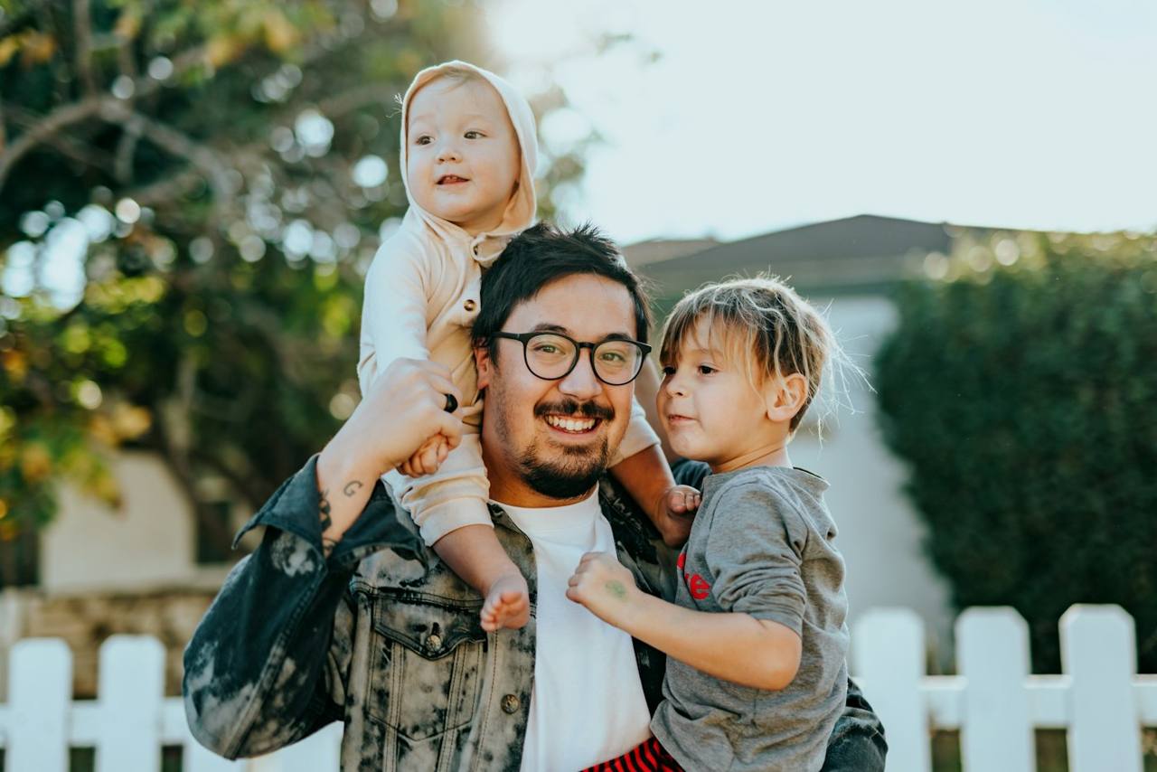 A father carrying his two young children on his shoulders