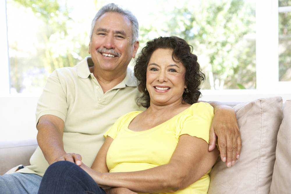 An older couple smiling together on a couch at home