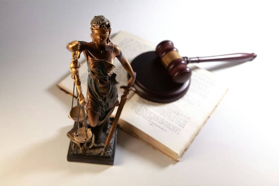 A gavel and a statue of justice resting on an open law book