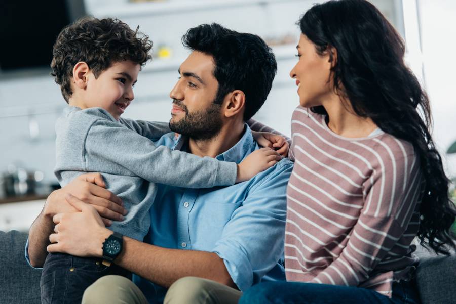 A father hugging his young son while the mother smiles beside them